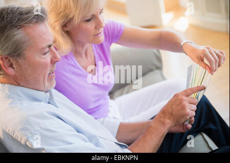 Portrait of couple sitting on sofa looking at sheet of paper Stock Photo