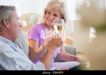 Portrait of couple sitting on sofa drinking white wine Stock Photo