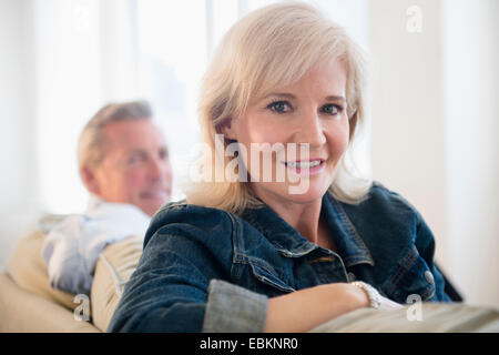 Portrait of woman wearing denim jacket sitting on sofa Stock Photo