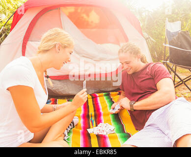 Couple playing cards in front of tent Stock Photo