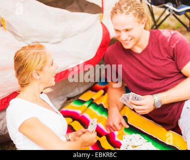 Couple playing cards in front of tent Stock Photo