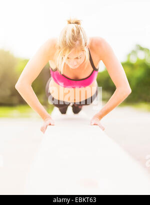 Woman doing pushups outdoors Stock Photo