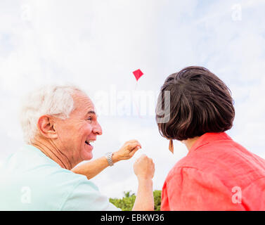 Low-angle view of couple flying kite together Stock Photo