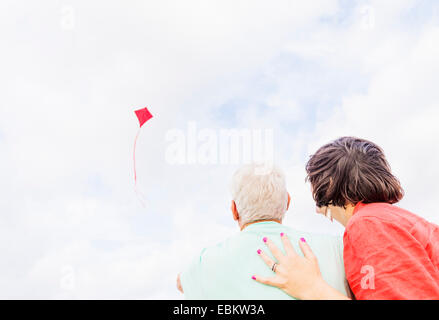 Low-angle view of couple flying kite together Stock Photo