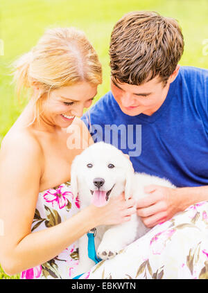 Portrait of young couple caressing white puppy Stock Photo