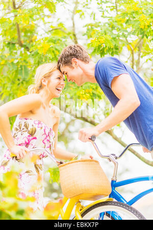 USA, Florida, Jupiter, Portrait of young couple sitting on bicycles, touching foreheads, laughing Stock Photo