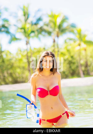 USA Florida Jupiter Portrait of young woman wearing bikini holding snorkel and scuba mask standing in waters of tropical lagoon Stock Photo