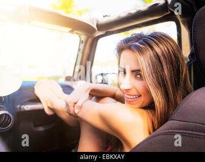 USA, Florida, Jupiter, Portrait of young woman sitting in car with legs on dashboard
