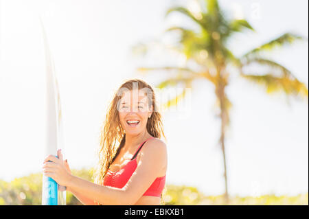 USA, Florida, Jupiter, Portrait of young woman holding surfboard on beach Stock Photo