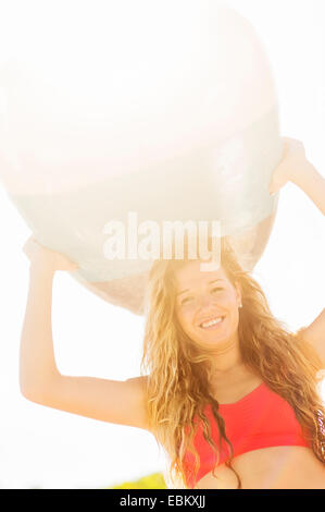 USA, Florida, Jupiter, Portrait of young woman holding surfboard over head Stock Photo