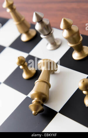 Classic chess game - fallen brass king on chessboard Stock Photo