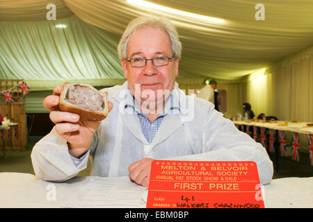 Melton Mowbray, Leicestershire, UK. 2nd Dec 2014.  One of the judges, Matthew O'Callaghan shows of one of the winning pork pies made by Walkers of Charnwood. Credit:  Jim Harrison/Alamy Live News Stock Photo