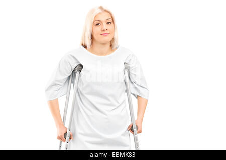 Female patient posing with crutches isolated on white background Stock Photo