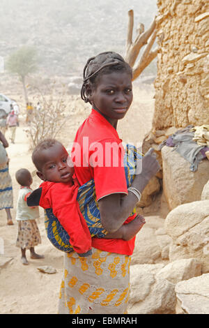 Woman of the Mafa ethnic group carrying a baby on her back, near Tourou, Far North, Cameroon Stock Photo