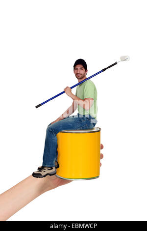 Man sat on paint tin Stock Photo