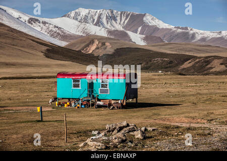 old residential container as a summer accommodation for the herdsmen in wasteland near Taskoemuer with snow-covered mountains, Kyrgyzstan, Djalalabad, Taskoemuer Stock Photo