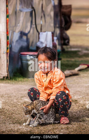 Kyrgyz girl playing with a cat, Kyrgyzstan, Lake Song Kul, Naryn Stock Photo