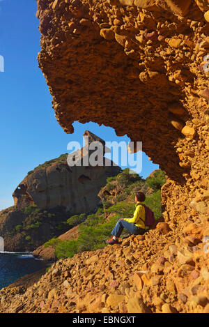 woman enyoing the view under rock spur, Calanque of Figuerolles, in the background a cliff called Grand Capucin, France, Calanques National Park, La Ciotat Stock Photo