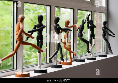 Row of artist mannequins along windowsill. Stock Photo
