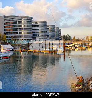 marina and Five Boats office buildings, angler in foreground , Germany, North Rhine-Westphalia, Ruhr Area, Duisburg Stock Photo