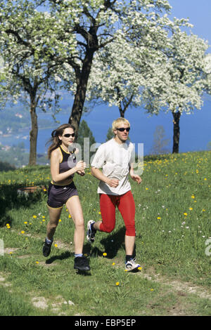young pair jogging over field path in spring Stock Photo