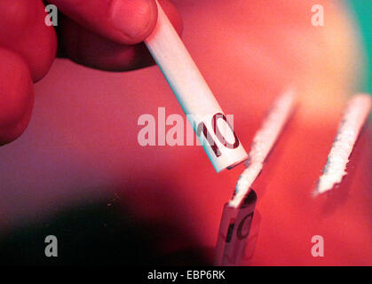 drug consumer snorting through a rolled 10 Euro bill two cocaine lines prepared on the table Stock Photo