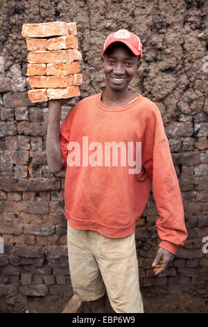 worker standing with clay bricks in front of mud wall, Burundi, Karuzi, Buhiga Stock Photo