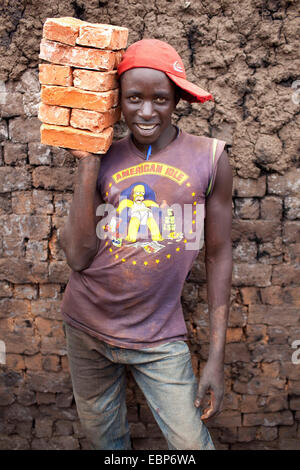 worker standing with clay bricks in front of mud wall, Burundi, Karuzi, Buhiga Stock Photo