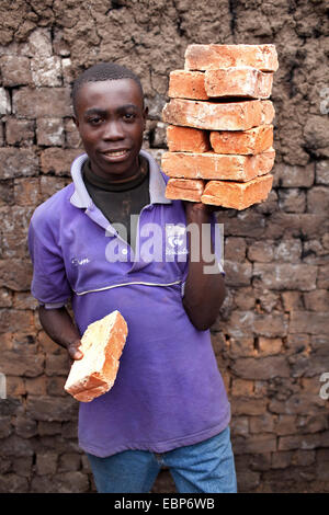 worker standing with clay bricks in front of mud wall, Burundi, Karuzi, Buhiga Stock Photo