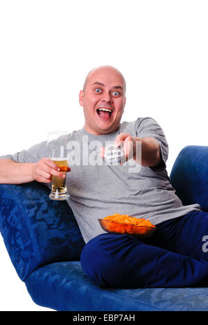 man with beer, chips and remote control sitting on sofa Stock Photo