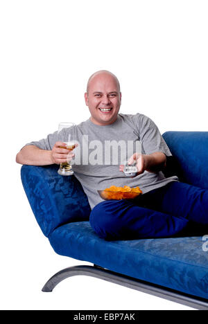 man with beer, chips and remote control sitting on sofa Stock Photo