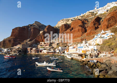 Ia, Santorini, South Aegean, Greece. View along the waterfront at Ammoudi Bay, red volcanic cliffs towering above. Stock Photo