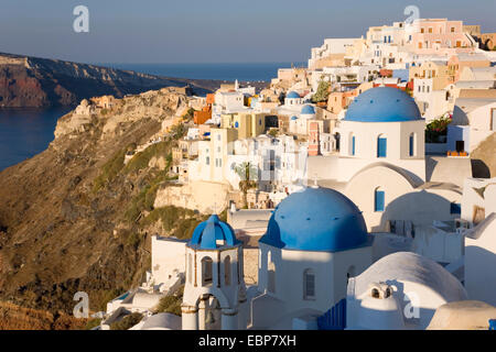 Ia, Santorini, South Aegean, Greece. The village at sunrise, typical blue-domed churches prominent. Stock Photo