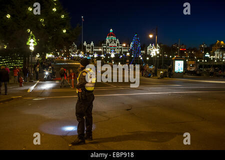 Policeman on duty for annual Santa Claus parade with Legislative Buildings at twilight-Victoria, British Columbia, Canada. Stock Photo