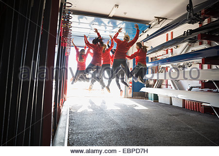 Rowing team jumping for joy in boathouse
