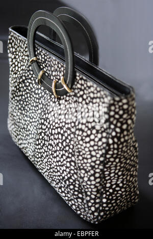 Pony hair black and white dot womens hand bag top handle with gold detail vertical standing up Stock Photo
