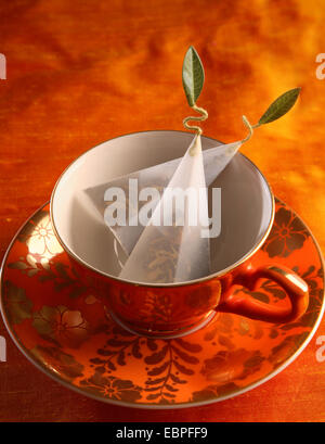 orange ornate teacup with decorative tea on a orange saucer with orange background Stock Photo