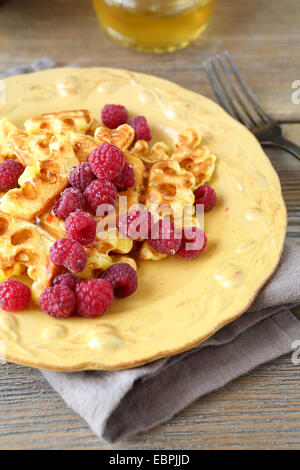 Waffles and raspberries on a plate, wooden boards Stock Photo