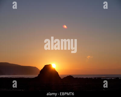 Sun behind Black Rock, Widemouth Bay, Bude, Cornwall, UK Stock Photo