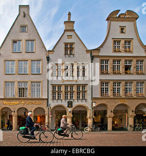 two female cyclists in front of a row of houses with arches at the Prinzipalmarkt, Germany, North Rhine-Westphalia, Muensterland, Muenster Stock Photo