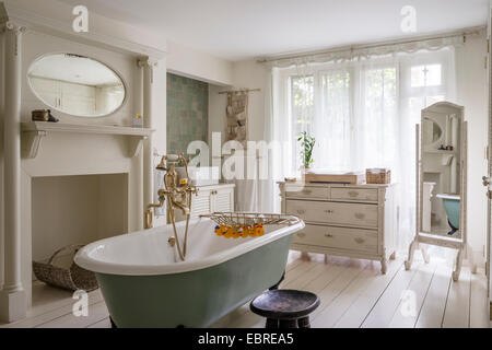 Freestanding roll-top bath with brass fittings in North London home Stock Photo