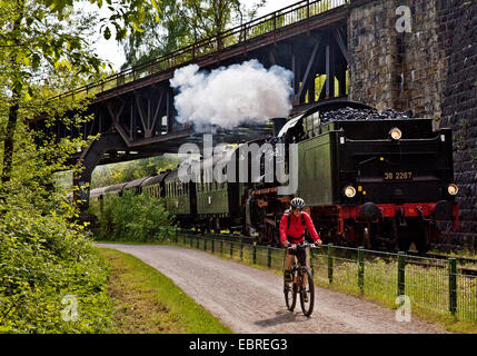 cyclists on Ruhr-Valley Cycleway next to historical steam engine, Germany, North Rhine-Westphalia, Ruhr Area, Witten Stock Photo