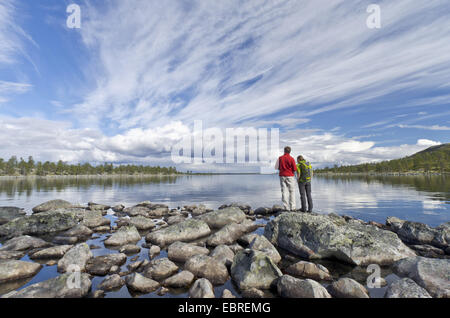 couple standing at the lakefront and looking to Rogen lake, Sweden, Haerjedalen, Naturreservat Rogen Stock Photo