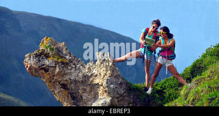 two young female wanderers on a rock spur looking at a map, France, Savoie, Vanoise National Park Stock Photo