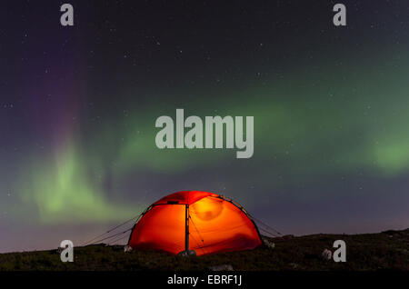 Northern Lights (Aurora borealis) over an illuminated tent, Norway, Vestland, Fylke M°re og Romsdal Stock Photo