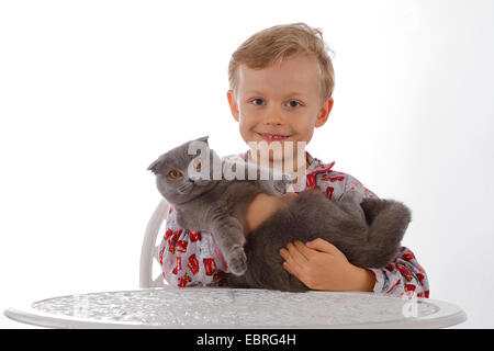 domestic cat, house cat (Felis silvestris f. catus), smiling child in pyjama with cat on arm Stock Photo