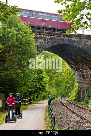 two tourists on Segways at Ruhr Valley Cycleway, historical railbus on viaduct, Germany, North Rhine-Westphalia, Ruhr Area, Witten Stock Photo