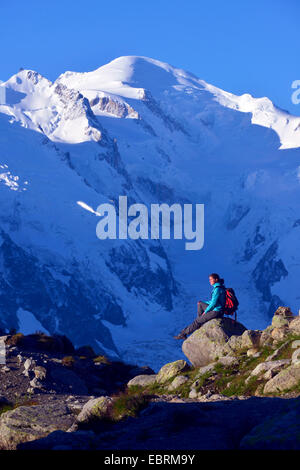 female mountain hiker sitting on Aiguilles Rouges in the opposite the Mont Blanc massif, France, Haute-Savoie, Chamonix Stock Photo