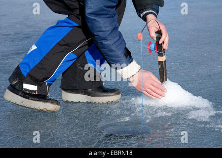 Ice fisher fixing the fishing rod on frozen lake, Sweden Stock Photo