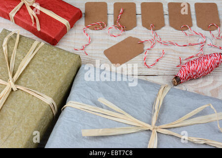 Overhead shot of a group of blank gift tags surrounded by wrapped Christmas presents on a white rustic table. Horizontal format Stock Photo